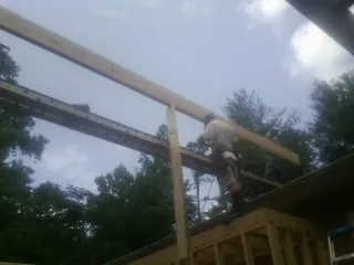 Carpenter setting a ridge beam over a new addition frame — Ice Dam Removal by Roofing Brothers in Alto
