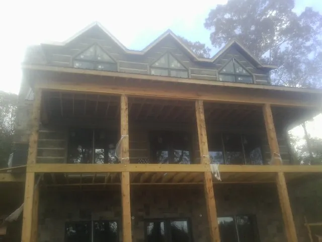 Dormers and porch framing on a large log home under construction — Roof Coating work by our crew in Alto