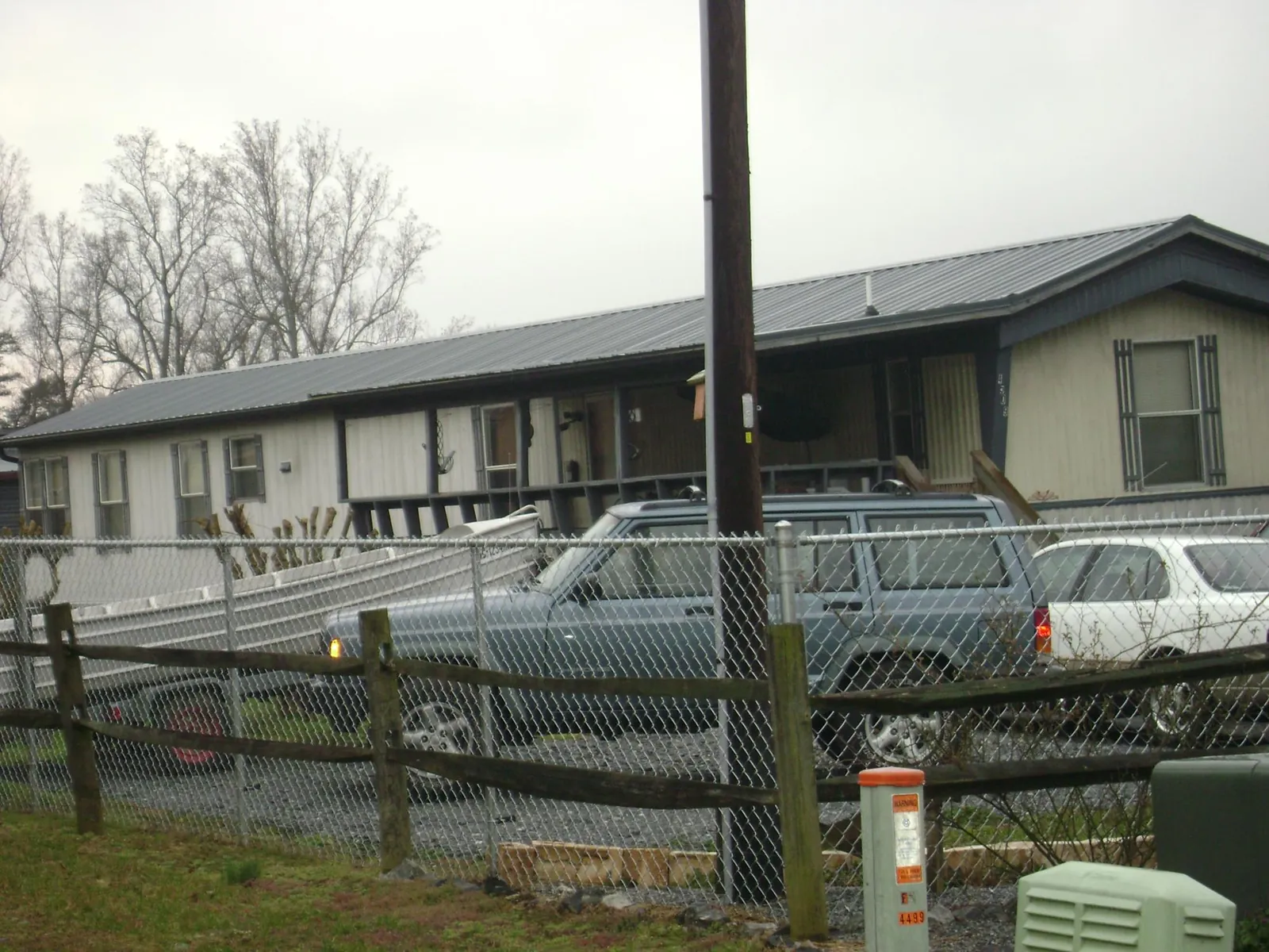 Dark metal roof on a long single story building behind a chain link fence in Alto