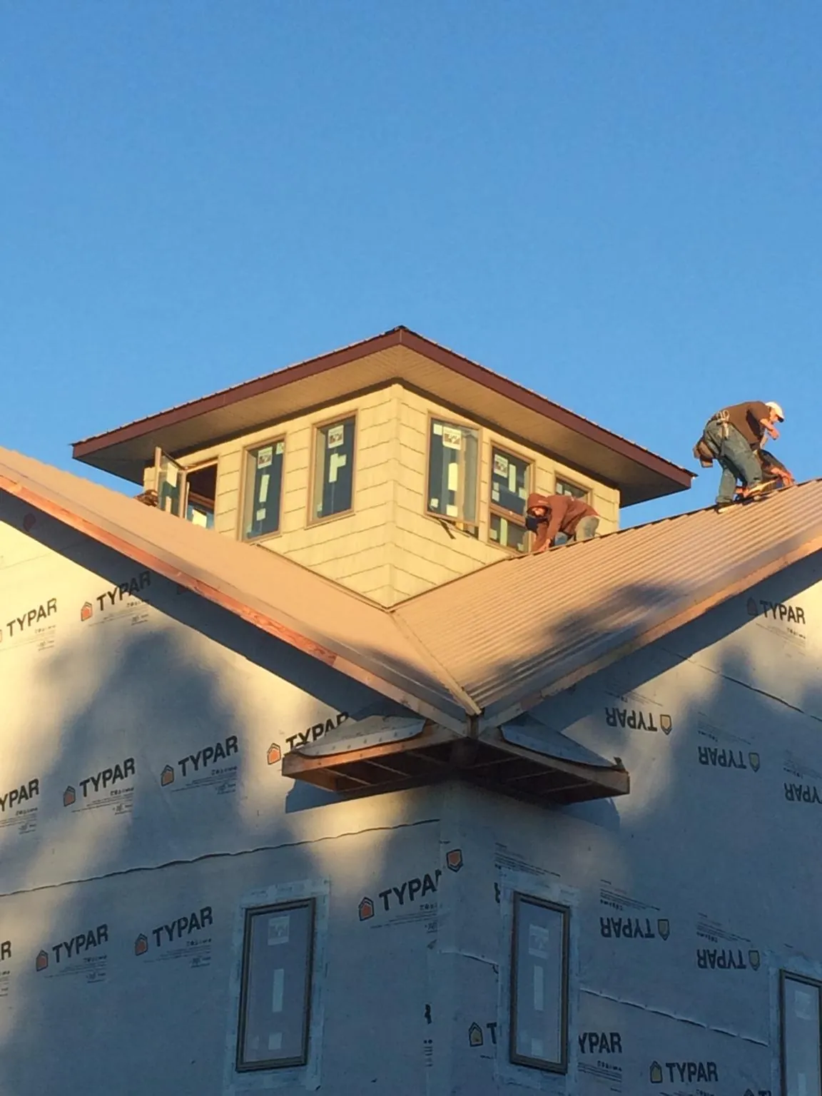 Roofers working around a rooftop cupola on a new metal roof at sunset — Roof Waterproofing in Alto by Roofing Brothers